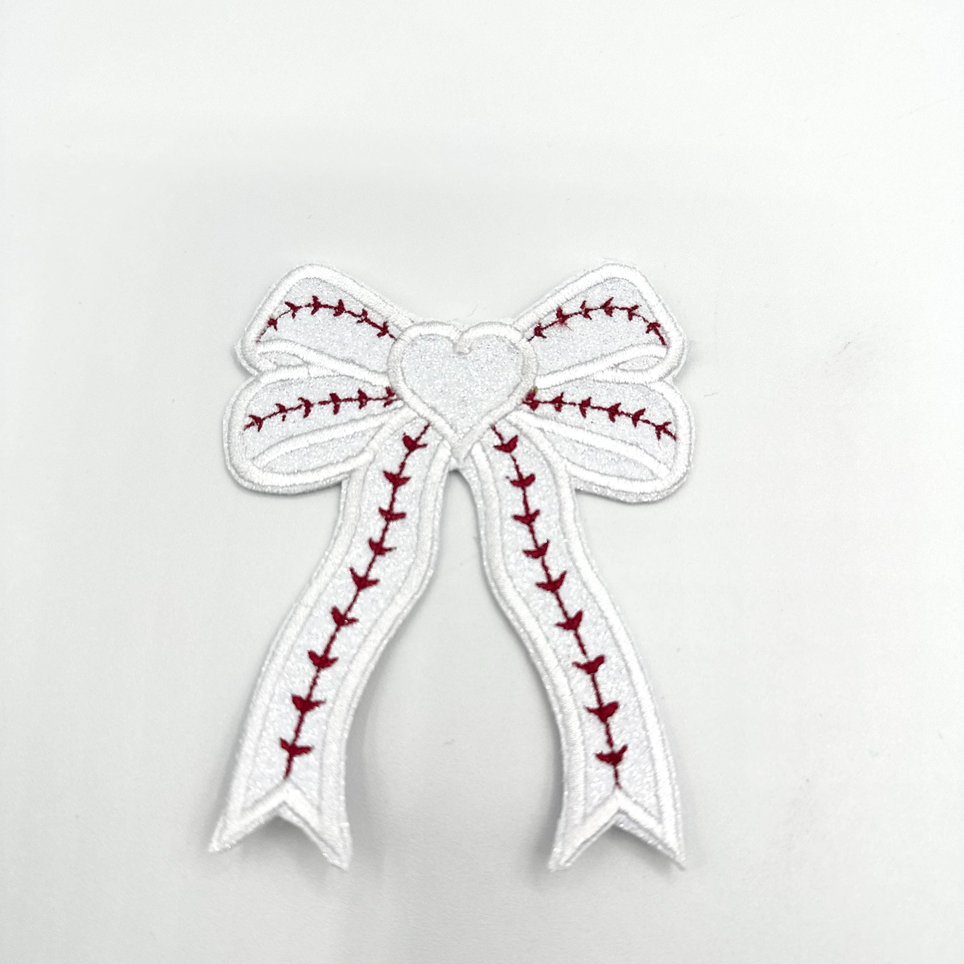 Baseball Custom Embroidered Side Bow Patch| Iron On| Side Bow Applique| Glitter Side Bow|  Embroidered Side Bow| Coquette Side Bow| Patches
May include: A white bow with red stitching in the shape of a baseball stitch. The bow has a white heart in the center.