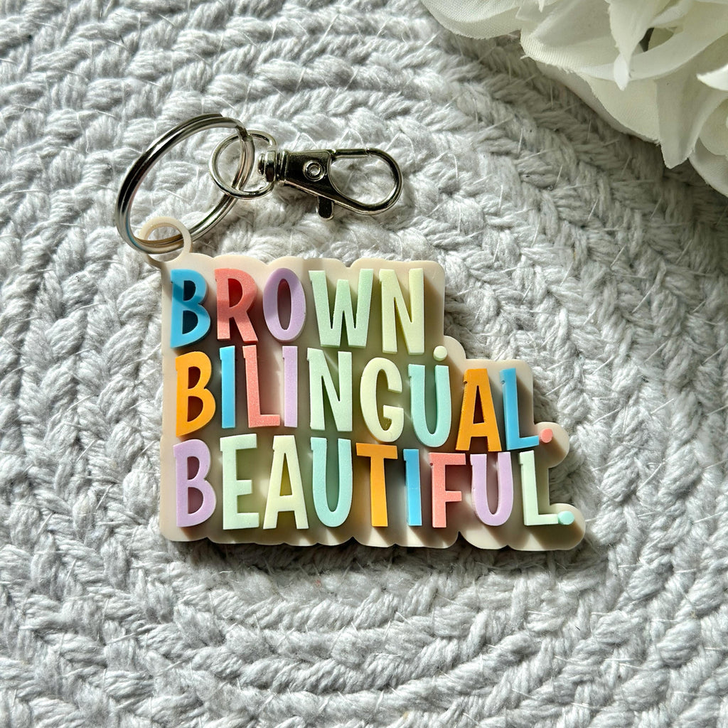 Brown. Bilingual. Beautiful Keychain| Acrylic Keychain| Gifts for Teens| Backpack Tag| Hispanic| Latino| Gift Ideas| Latinas| Boho| Inspire
May include: A keychain with the words &#39;BROWN&#39;, &#39;BILINGUAL&#39;, and &#39;BEAUTIFUL&#39; in rainbow colors. The keychain is made of white plastic and has a silver key ring.