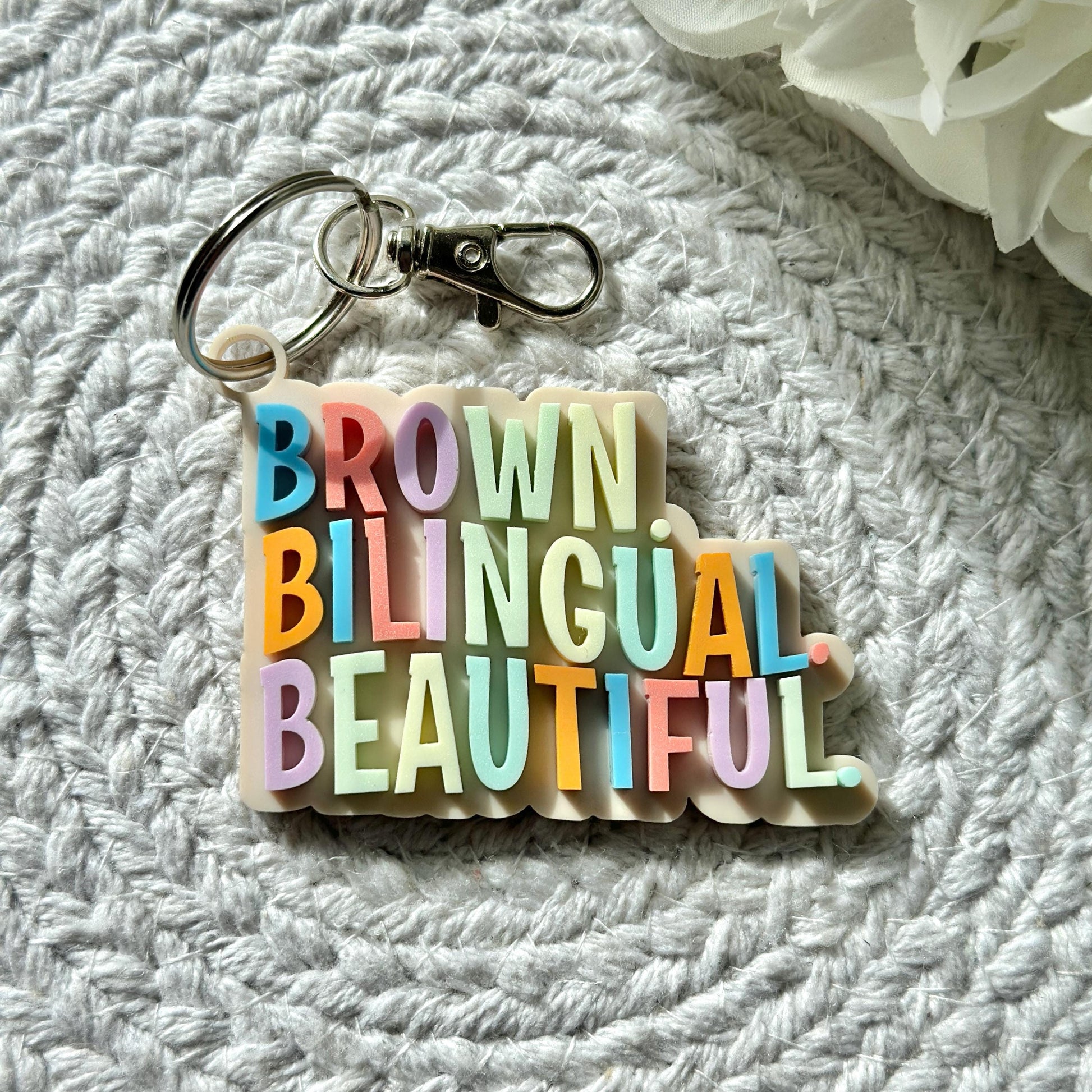 Brown. Bilingual. Beautiful Keychain| Acrylic Keychain| Gifts for Teens| Backpack Tag| Hispanic| Latino| Gift Ideas| Latinas| Boho| Inspire
May include: A keychain with the words &#39;BROWN&#39;, &#39;BILINGUAL&#39;, and &#39;BEAUTIFUL&#39; in rainbow colors. The keychain is made of white plastic and has a silver key ring.