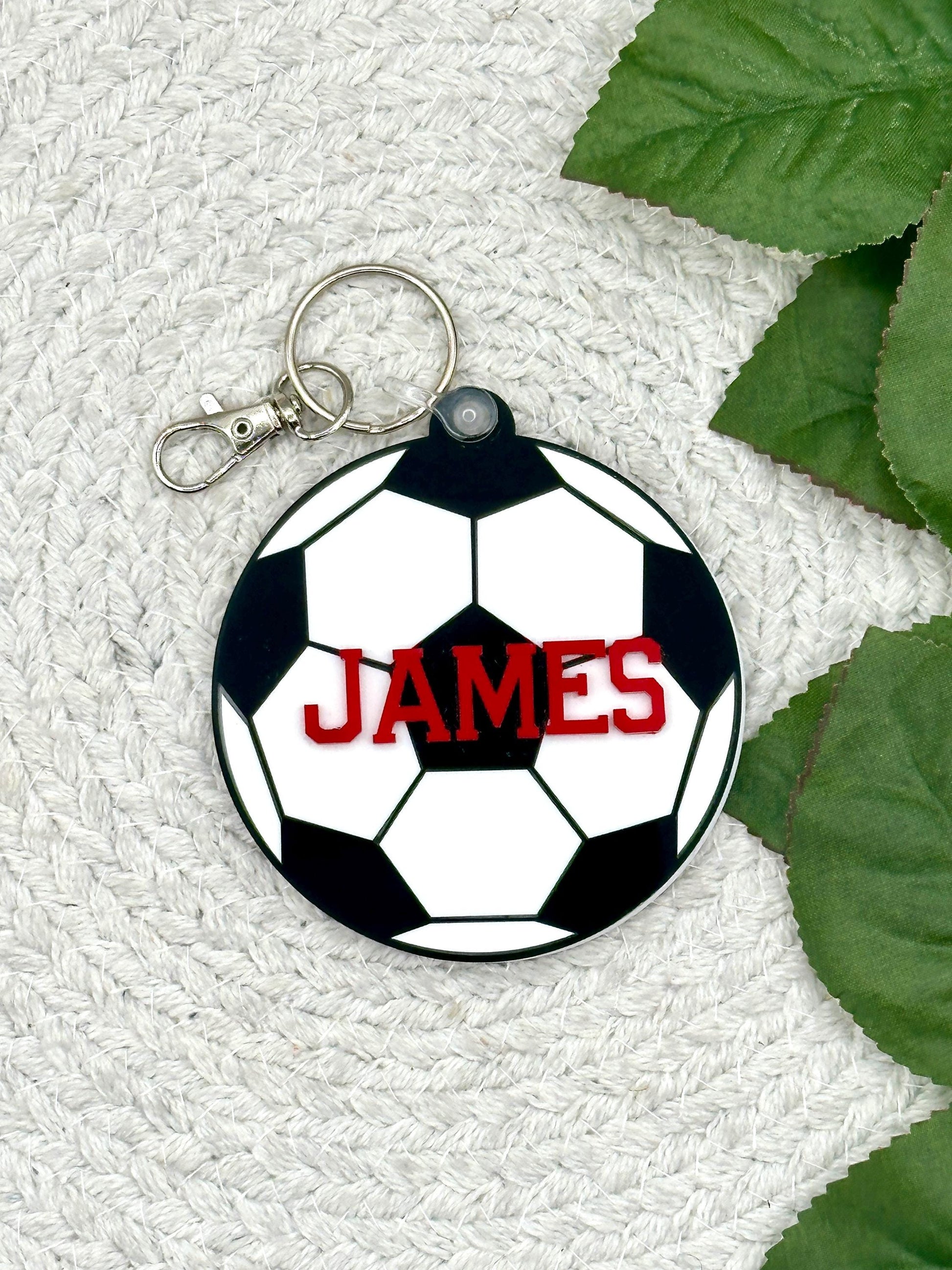 Soccer Name Tag| Soccer| Sport Keychains| Bag Tag| Luggage| Custom Sports Tag|Custom Keychain| Personalized Soccer Keychain| Backpack Tags

May include: A black and white soccer ball keychain with a red name &#39;JAMES&#39; on it. The keychain has a silver metal ring and a silver metal clip.