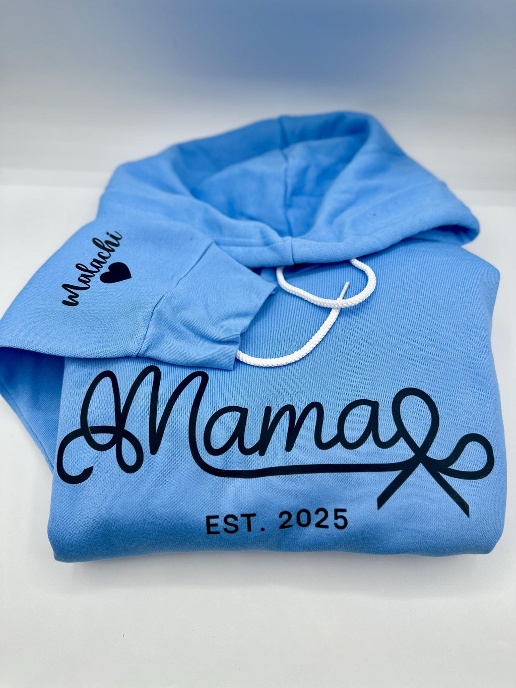 Mama Est Sweater| Custom Mama Est 2024 Sweater| Mom Sweatshirt| Mom Gift| New Mom Gift| DTF Fleece Hoodie Custom Sweater Bella + Canva

May include: A light blue hooded sweatshirt with the text &#39;Mama Est. 2025&#39; in black. The text &#39;Malachi&#39; with a black heart is on the left sleeve of the sweatshirt.