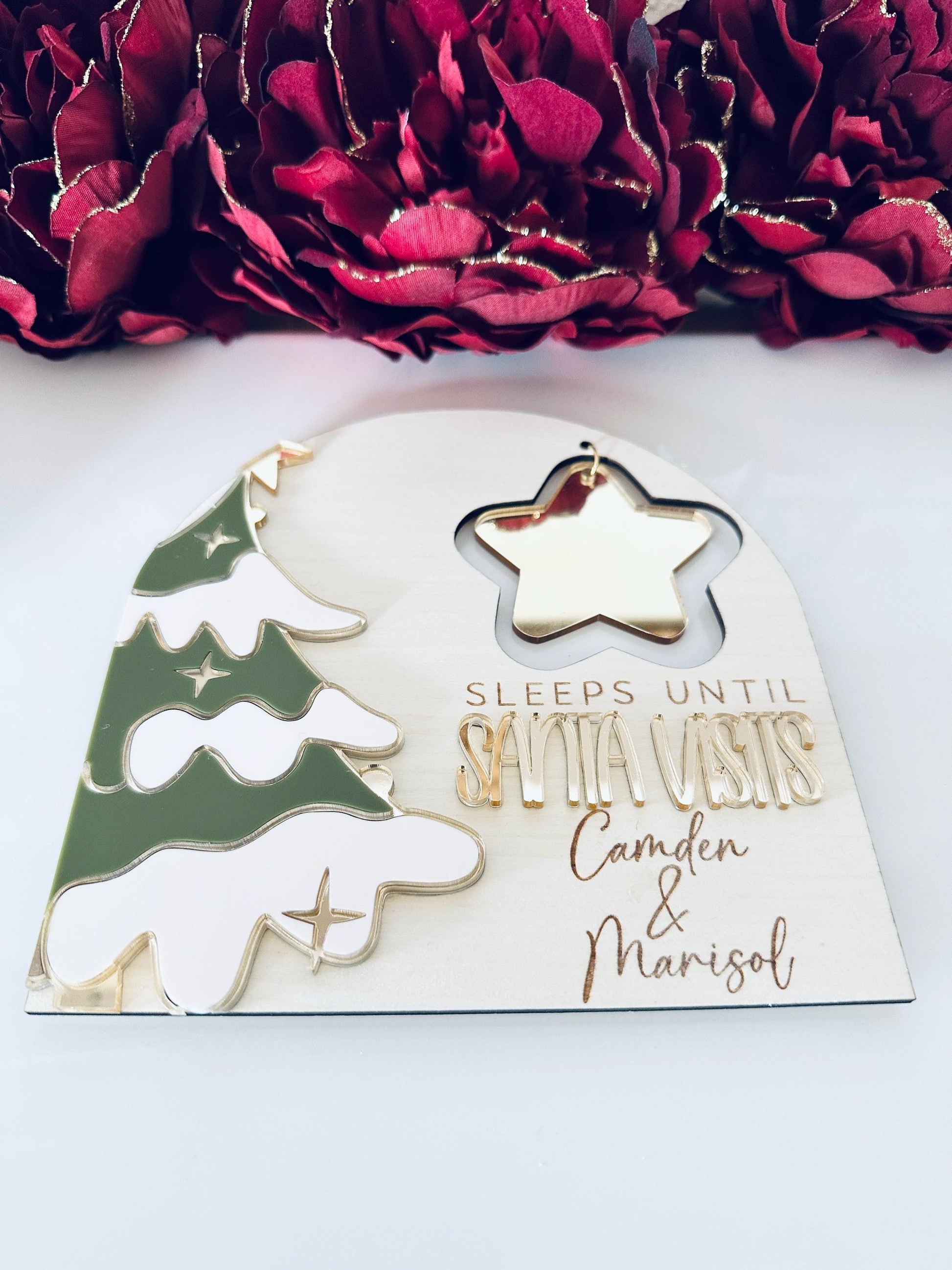 Layered acrylic and maple wood ‘Sleeps Until Santa Visits’ countdown sign with magnetic star, green tree accents, gold mirror details, and holiday decor background.