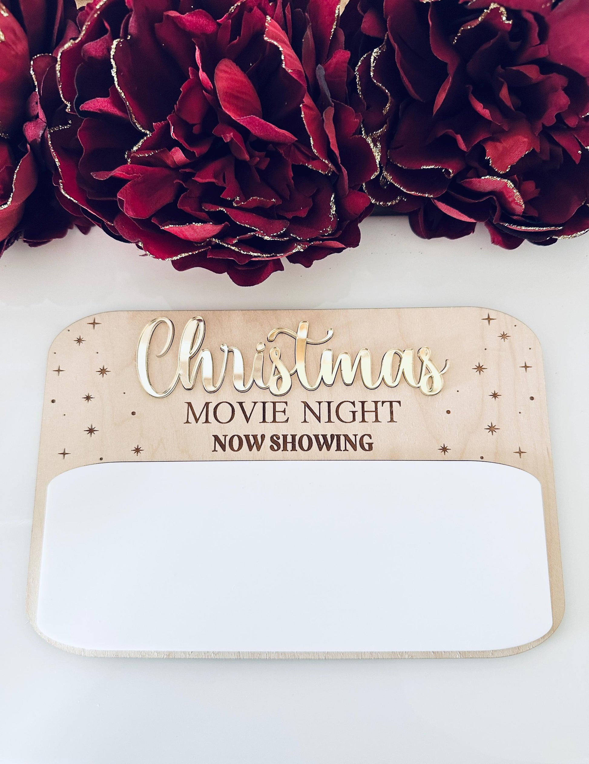 Christmas Movie Night board made of maple wood and white acrylic with gold lettering, reusable dry-erase writing space, holiday decor background.